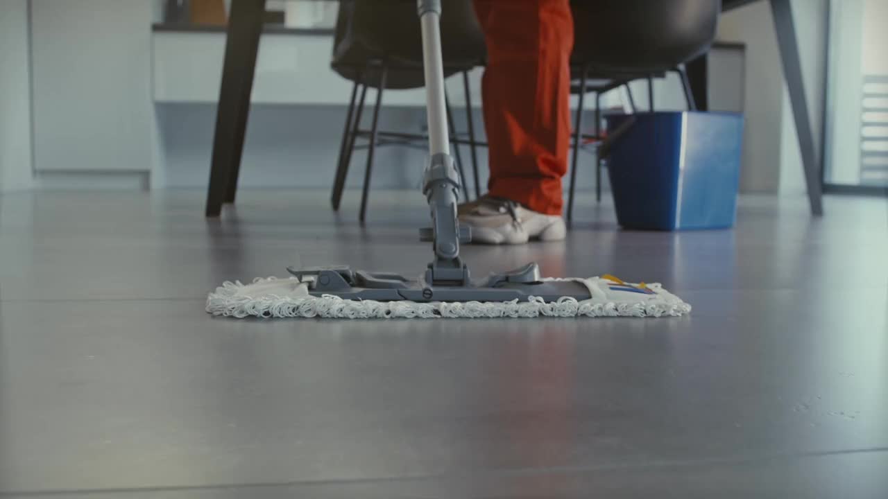 Cleaner using a mop to clean the floor.
